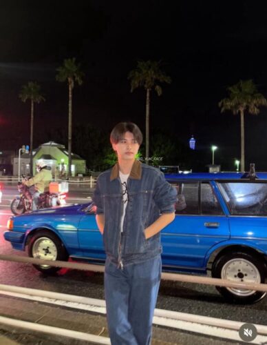 夜、旧車を背景にしたYUKI、奥に同じ青いタワーが見える