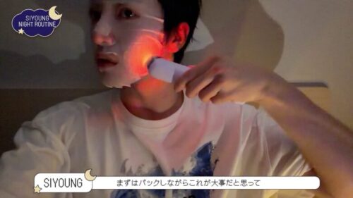シートマスクをつけながら赤色LEDの美顔器を頬に当てるSIYOUNG